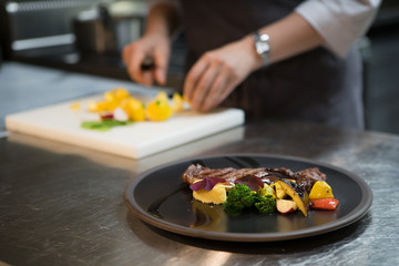 Chef puts the dish on a plate. Preparing to serve.