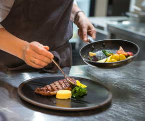 Chef puts the dish on a plate. Preparing to serve.