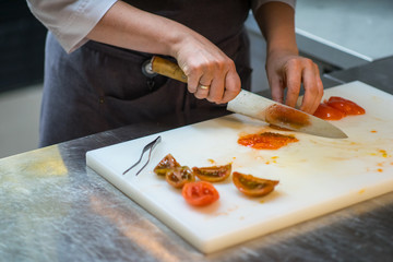 Cutting tomatoes with a kitchen knife. Chef. A restaurant.