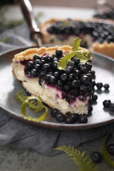 A piece of blueberry cheesecake with blueberries on plate on light gray background. Vintage dishes and textile.