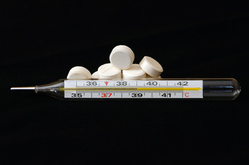 Thermometer is a black background and white pills