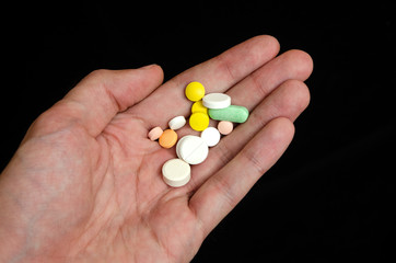 man holding a pill. Medication.Black background.
