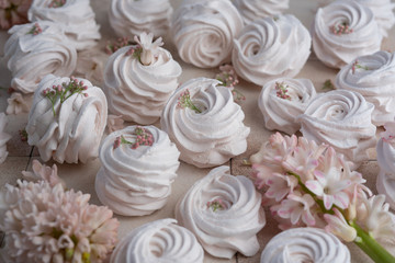 Meringues and spring pink flowers on vintage background