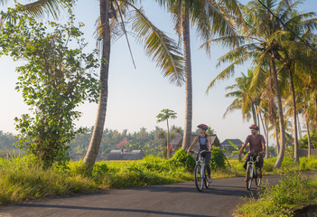 Fototapeta premium Happy young couple riding bicycles along road in summer. Leisure and lifestyle concept