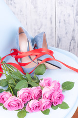 A large bouquet of pink roses on a blue chair in women's shoes with thin heels. New shoes and flowers. A gift for a woman on Valentine's Day. Copy space.