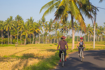 Fototapeta na wymiar Happy young couple riding bicycles along road in summer. Leisure and lifestyle concept