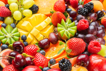 Healthy fruit background filled with strawberries raspberries oranges plums apples kiwis grapes blueberries mango persimmon pineapple, selective focus