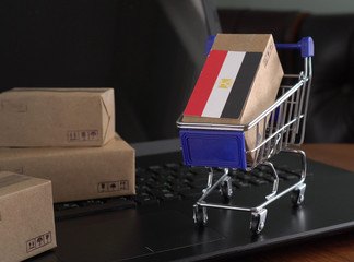 Paper box with a flag of Egypt in a shopping cart on a laptop keyboard. Trade at an international level