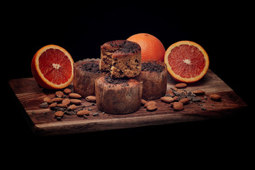 A bread board with sliced oranges and muffins
