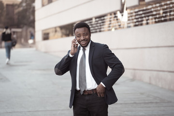 Portrait of handsome african american businessman walking in the city talking on mobile phone