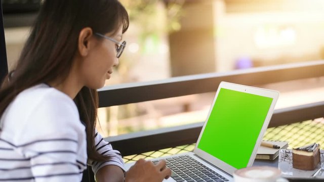 Asian Woman working at home on with laptop green screen. Over the shoulder shot of a business woman working in office interior on pc on desk, Office person using laptop computer.