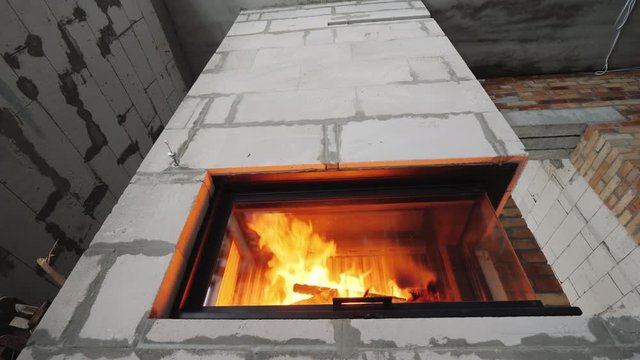 Low angle wide shot: Fireplace portal with a corner furnace in a house where repairs are not finished.