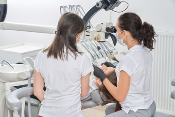 Obraz premium View from back of dentists and checking teeth of patient