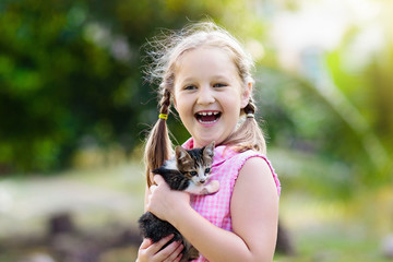 Little girl holding baby cat. Kids and pets