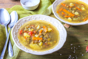 Delicious lentil soup in white plates on wooden background