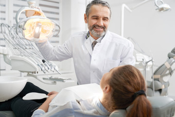 Cheerul dentist smiling, looking at patient.