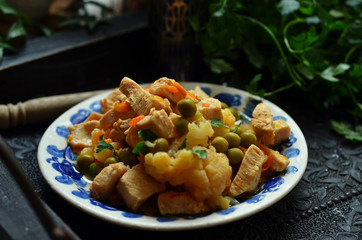 Chicken with peas and cauliflower on a rustic plate on a black tray