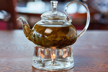 Milk Oolong tea stands in a glass teapot on a stand with a candle