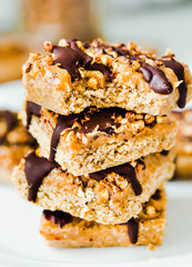 Organic homemade granola bars with date caramel and chocolate on white marble background.Close-up.