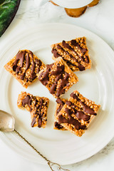 Granola bar dessert with oats, nuts and dates on a white marble table. Healthy lifestyle and raw vegan dessert concept. Top view.
