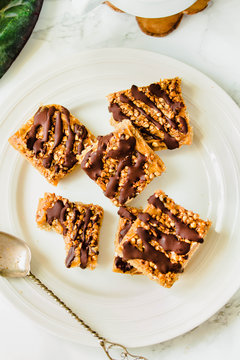 Granola bar dessert with oats, nuts and dates on a white marble table. Healthy lifestyle and raw vegan dessert concept. Top view.