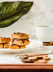 Organic Chocolate Granola bar cake. Slices with a cup of coffee on a white stone background. Plant based diet dessert.