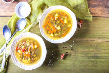 Delicious lentil soup in white plates on wooden background