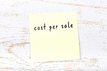 Yellow sticky note with handwritten text cost per sale