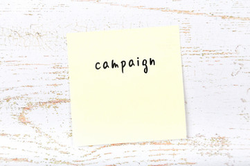 Yellow sticky note with handwritten text campaign
