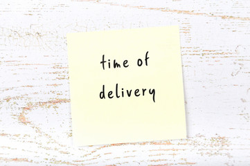 Yellow sticky note with handwritten text time of delivery