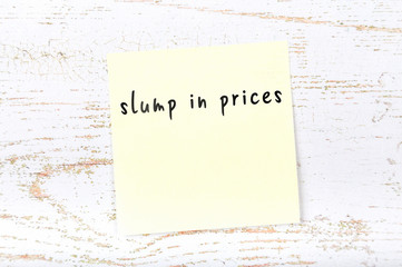 Yellow sticky note with handwritten text slump in prices