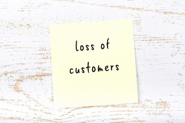 Yellow sticky note with handwritten text loss of customers