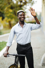 Portrait of handsome young african man waving hello near bike in the street. © F8  \ Suport Ukraine