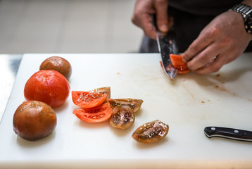 Cutting tomatoes with a kitchen knife. Chef. A restaurant.
