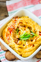 Traditional Middle east appetizer Hummus served with fresh pita bread and herbs, seasoned with extra virgin olive oil and paprika in white ceramic plate. Close-up.