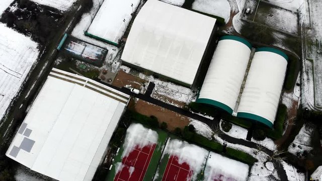 Aerial drone shot in 4K of a tennis court in winter with snow