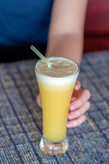 Woman hand holding a glass of fresh pineapple juice, close up