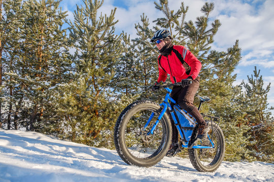 Man riding a mountain bike with big fat tires and helmet on a snow. Fat bike.