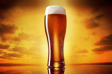 Glas klassisches indisches blasses IPA-Bier auf einem goldenen Hintergrund des Sonnenunterganghimmels.