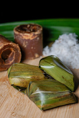Koci the malay glutinous rice ball served in banana leaf on white plate over wooden table