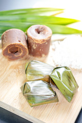 Koci the malay glutinous rice ball served in banana leaf on white plate over wooden table