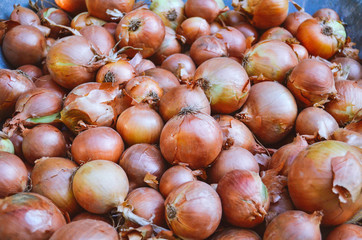 Onions in a wicker basket and next to it. A lot of onions in wicker vessels. Onions for cooking. Onions of different sizes. Vegetables for a healthy diet.