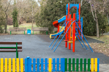 a colorful playground in the park of the city. empty play area for children, with colored appliances.