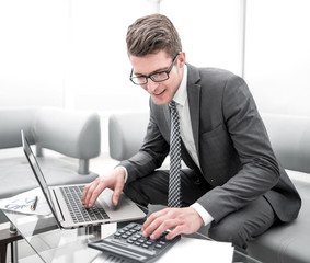 young businessman using calculator and laptop