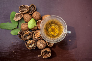 Close up of herbal organic tea of wall nut or walnut tea in a transparent glass cup with raw wall nut in shell and broken also.