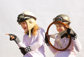 Twin sisters play race car driver sitting in their imaginative sports car. They play happily...