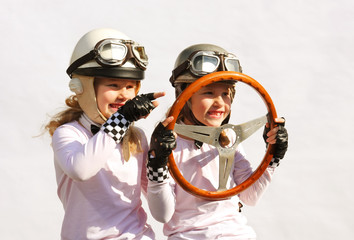 Twin sisters play race car driver sitting in their imaginative sports car. They play happily...