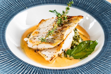 Fried fish fillet. Cod with sauce and herbs