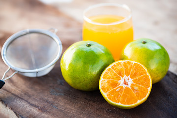 Green tangerine orange fruit and juice on wooden table