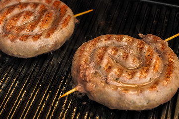 Fried spiral sausages on an electric barbecue BBQ grill. Homemade menu.
